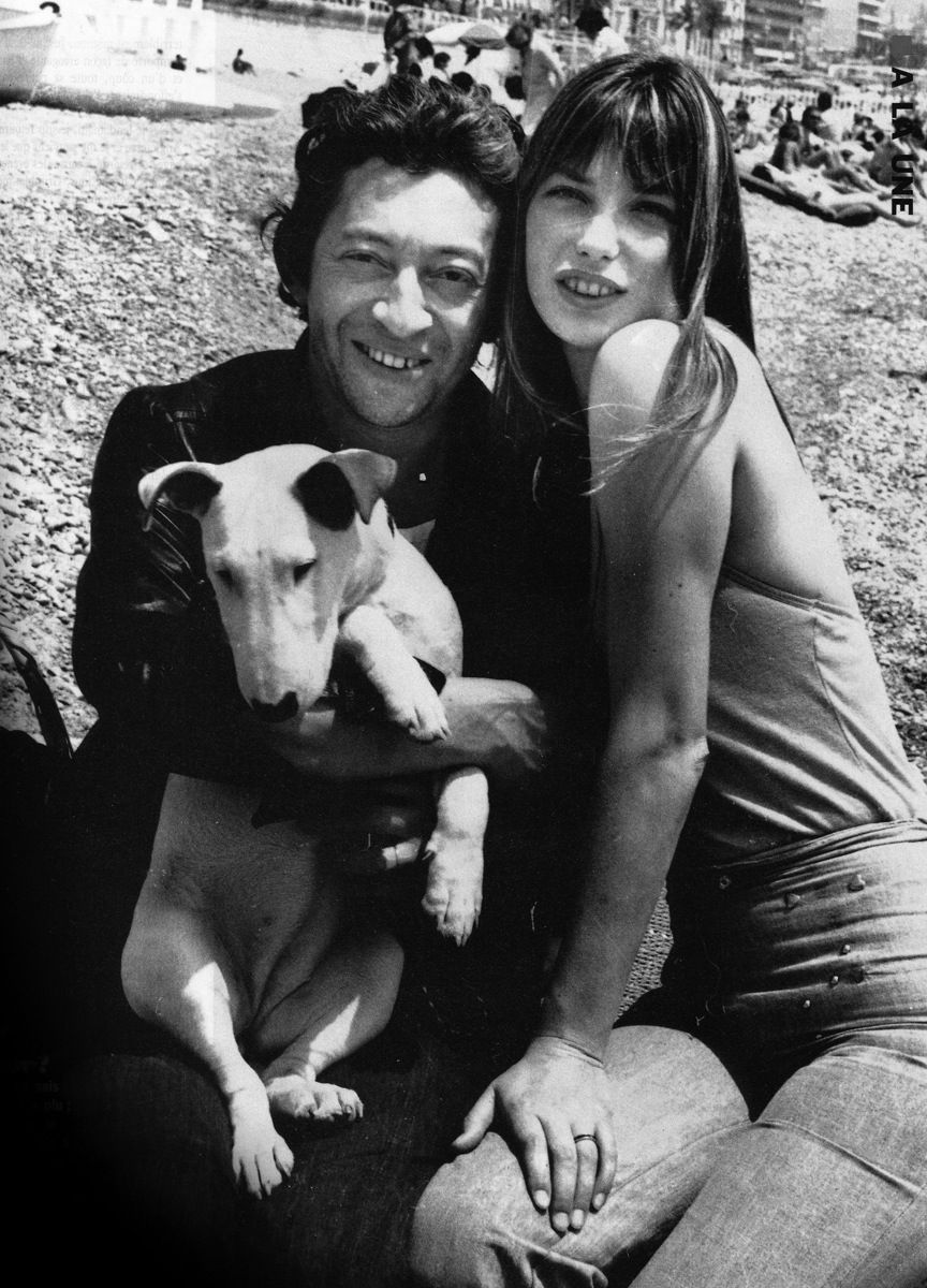Jane Birkin and Serge Gainsbourg sitting on the grass with their English Bull Terrier