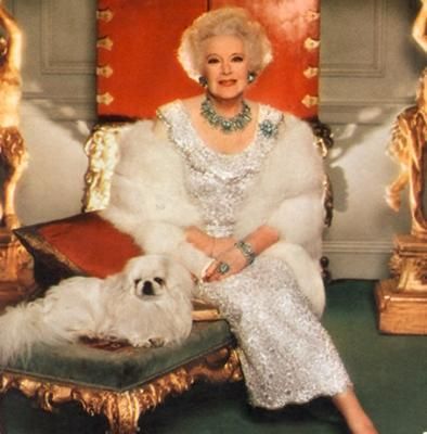 glamorous Barbara Cartland sitting on the chair next to her Pekingese