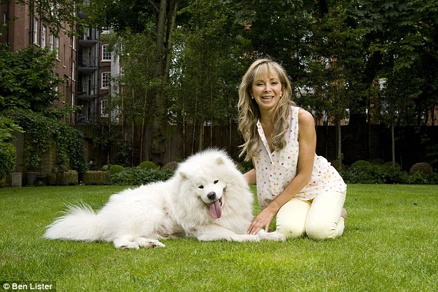 Annabel Karmel kneeling on the green grass with her Samoyed Dog lying down on the green grass