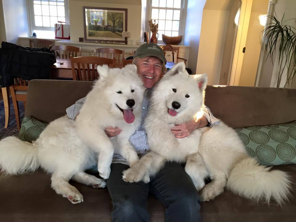 David McCormick sitting on a couch between his two Samoyed Dog