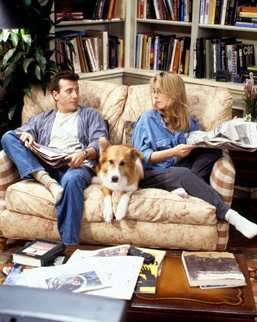 two persons sitting on the couch with a Border Collie in between them