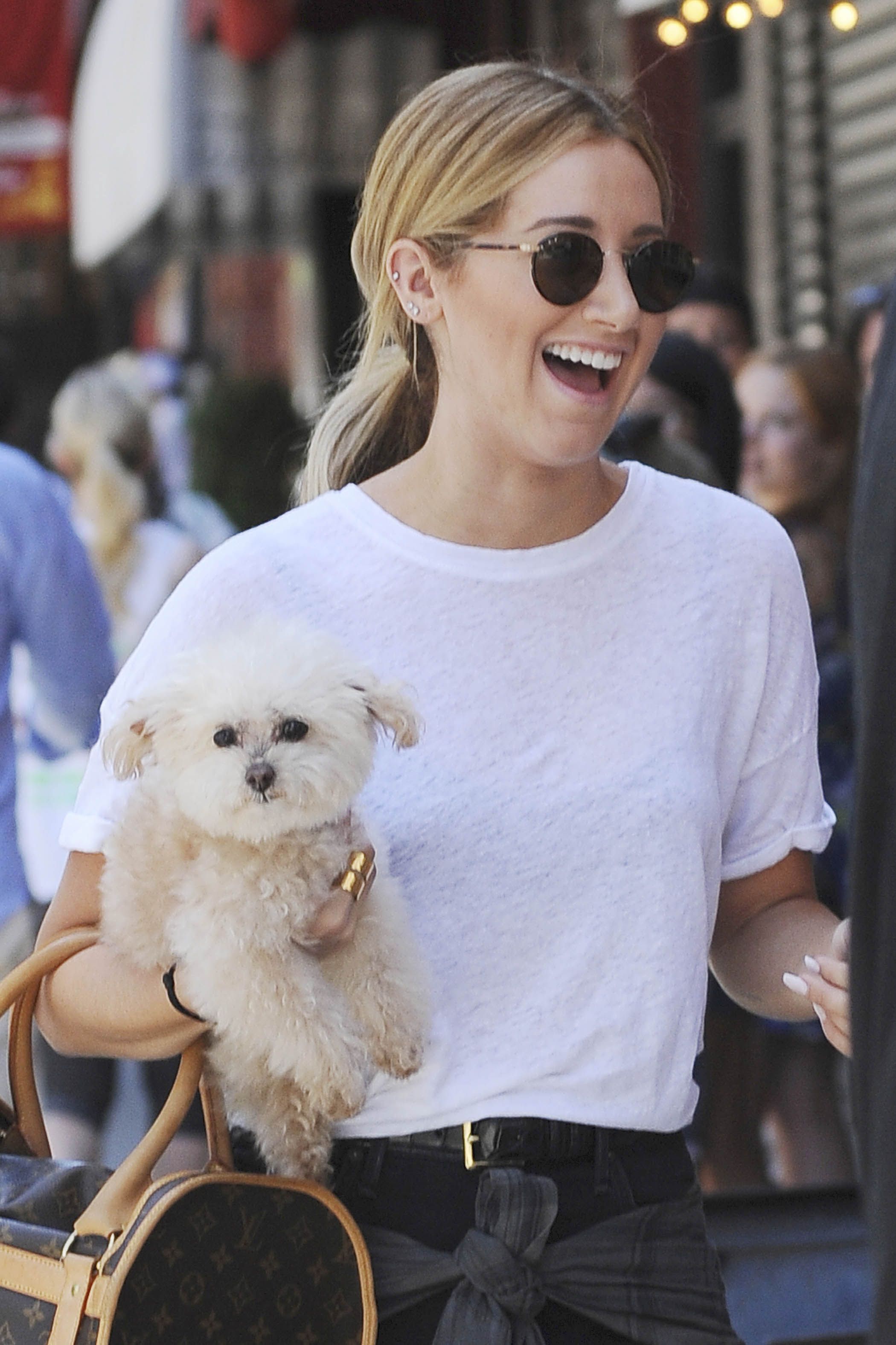 Ashley Tisdale walking in the street while carrying her Bichon Frise.