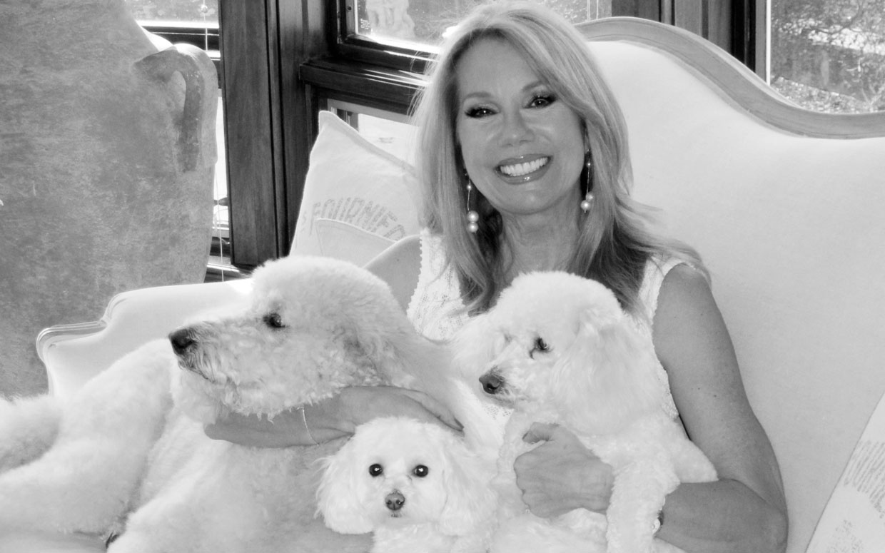 Kathie Lee sitting on the couch with her Bichon Frise and two other dogs