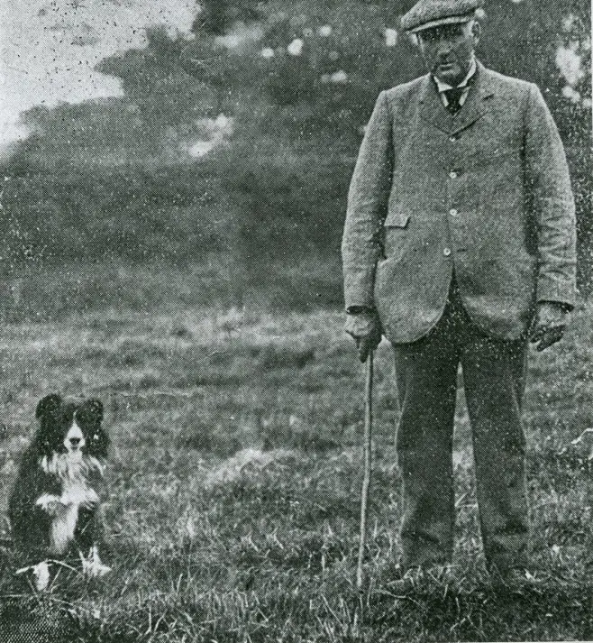 an old photo of Adam Telfer standing next to his Border Collie in the yard
