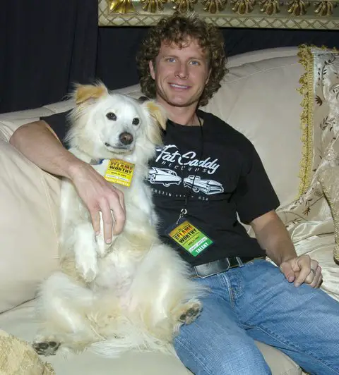 Dierks Bentley sitting on the sofa with his arms around his Border Collie next to him