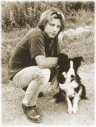 an old photo of Jon Bon Jovi next to his Border Collie who is sitting on the ground