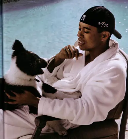 Tiger Woods sitting on chair beside the pool with his Border Collie