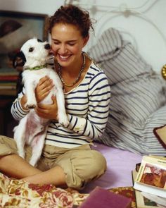 Natalie Portman sitting on the floor while her face is being licked by her Jack Russell