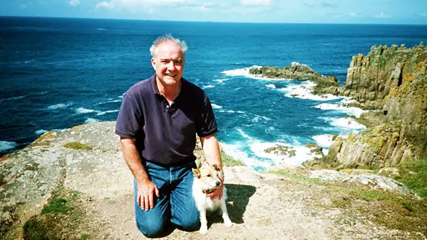 Rick Stein kneeling by the cliff with his Rick Stein