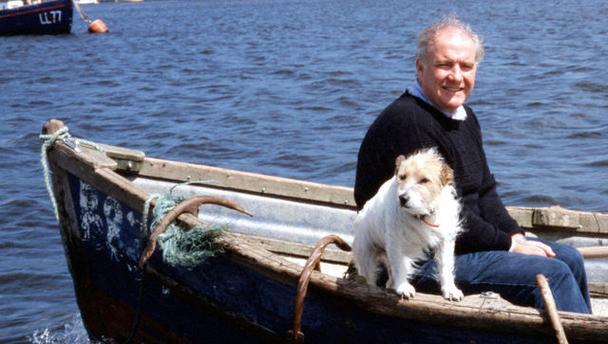 Rick Stein sitting inside a boat with his Jack Russell next to him