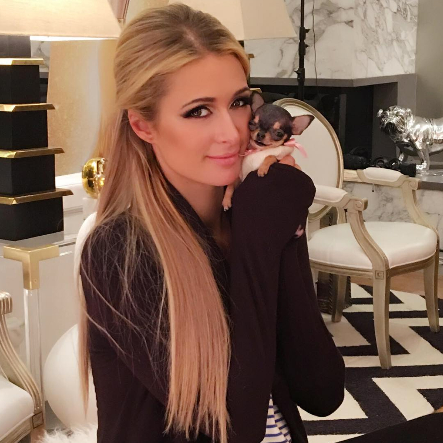 Paris Hilton holding her tiny Chihuahua close to her face