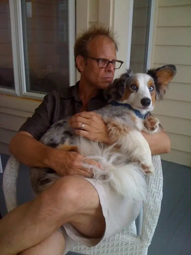 Alton Brown sitting on the chair with his Corgi on his lap