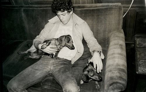 Lou Reed petting its dachshund dog while the other is on his lap