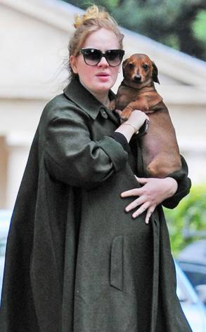 Adele standing outside her house while holding her Dachshund