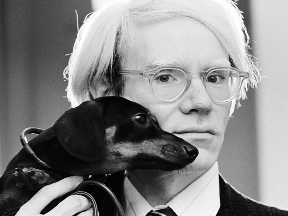 Andy Warhol holding her Dachshund close to his face