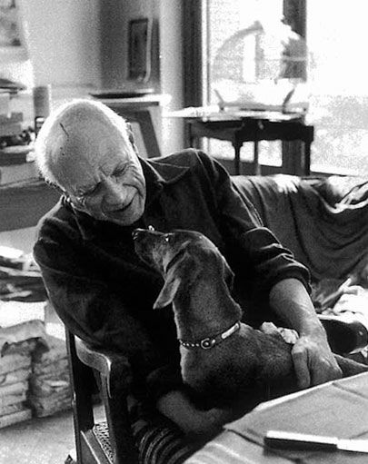 black and white photo of Picasso talking to his Dachshund in his lap