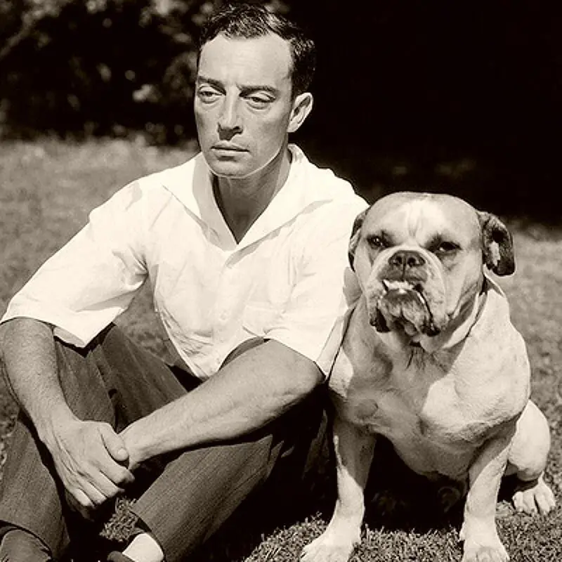 Buster Keaton sitting on the grass beside his English Bulldog