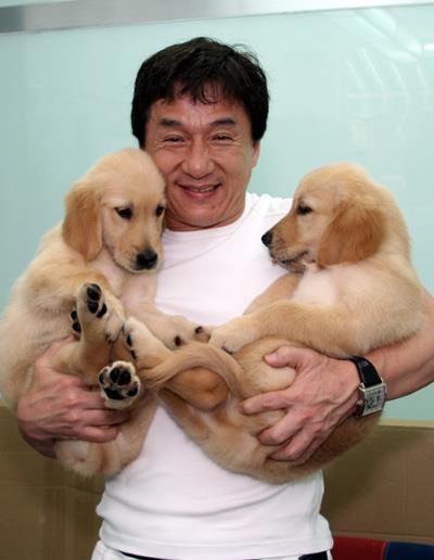 Jackie Chan carrying his two Golden Retriever puppies in his arms