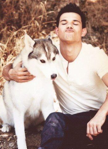 Taylor Lautne sitting on the ground while pouting his lips and putting his arms around his Husky sitting next to him