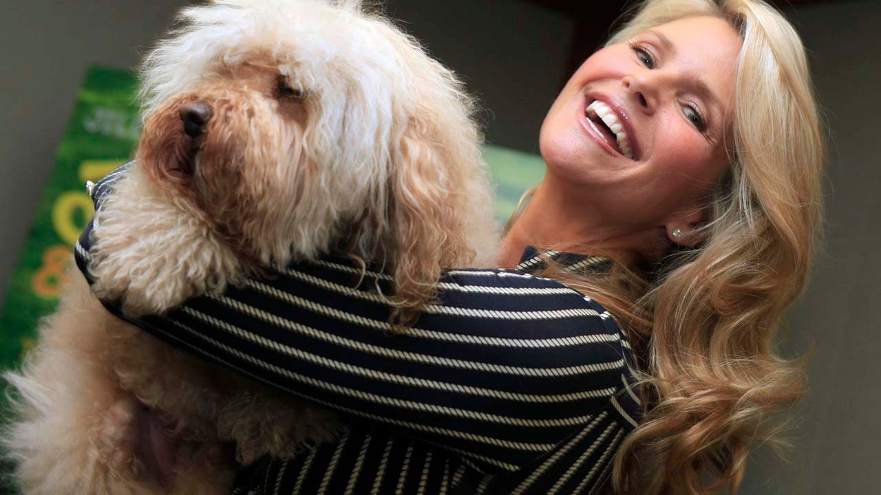 Christie Brinkley smiling while holding her Labradoodle in her arms