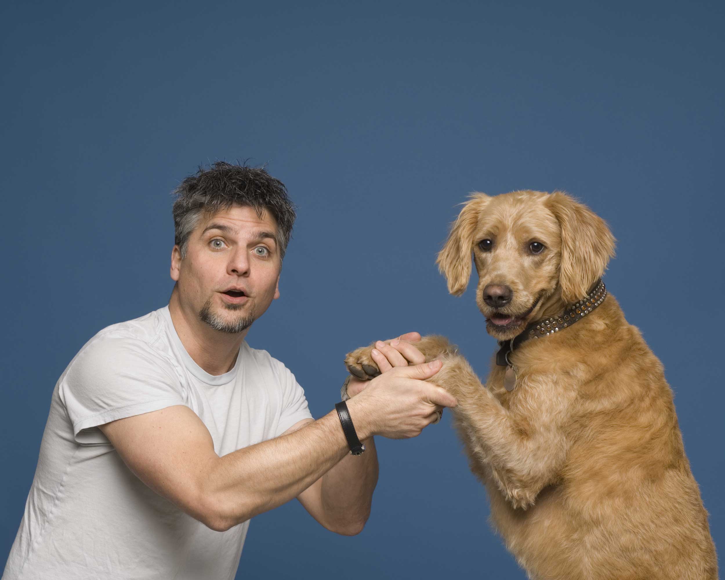 Garth Stein holding the paws of his Labradoodle who is standing in front of him