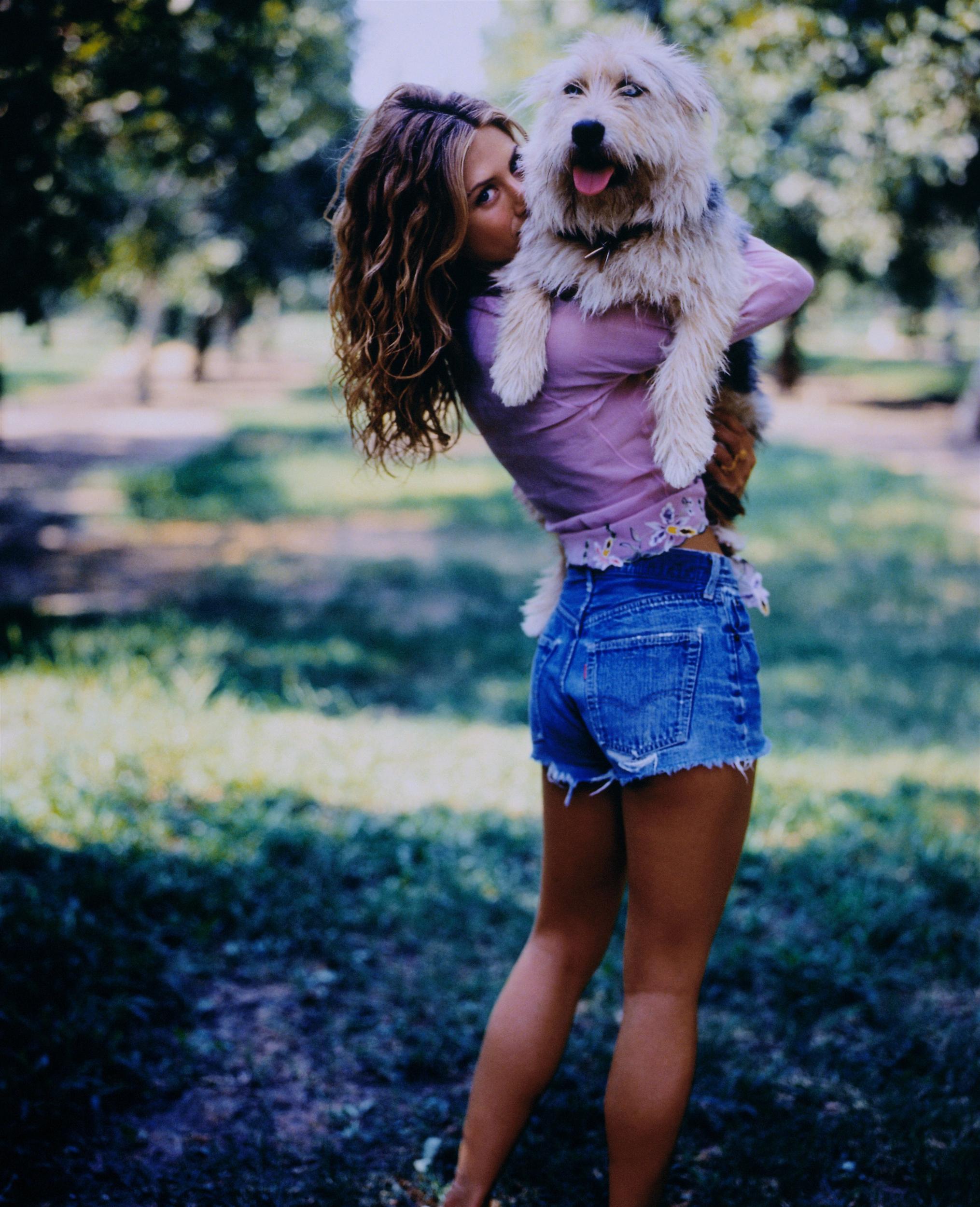 Jennifer Aniston in the orchard carrying her Labradoodle
