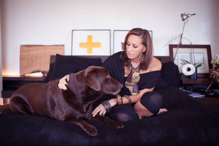 Donna Karan sitting on the couch while petting her Labrador lying next to her