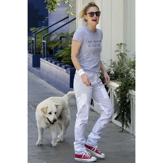 Drew Barrymore walking in the street with her white Labrador