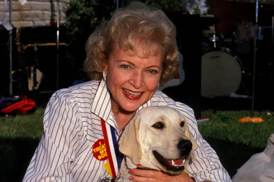 Betty White hugging her Yellow Labrador Retriever from behind