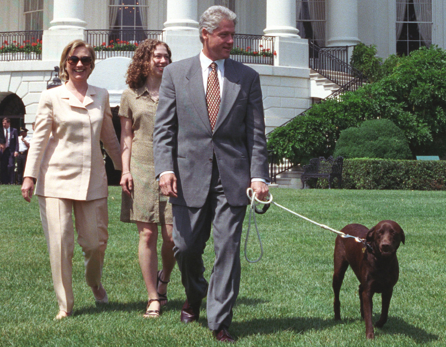 Bill Clinton walking in the backyard with his Labrador Retriever and two other girls