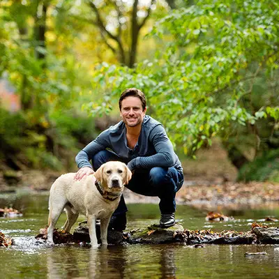 Charles Esten in the river with his Labrador Retriever