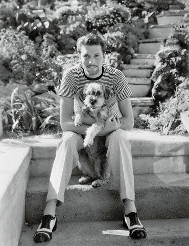 black and white photo of Laurence Olivier sitting in the garden with his Schnauzer in his lap