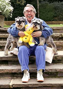 Ronnie Corbett sitting on the stairs with his two Schnauzer dogs