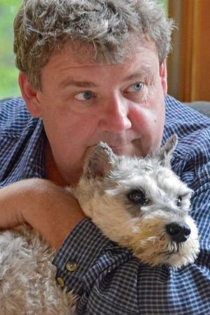 Tom Ryan hugging its Schnauzer dog