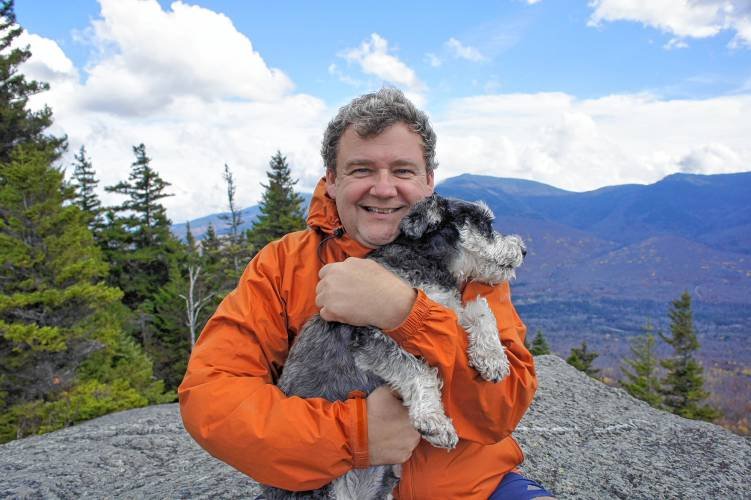 Tom Ryan on top of the mountain hugging his Schnauzer
