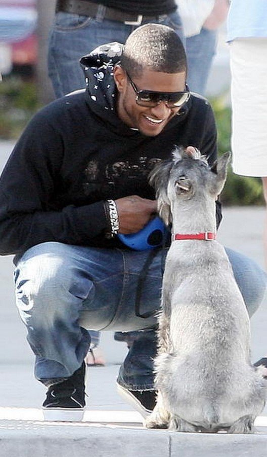 Usher smiling towards his Schnauzer siting on the pavement