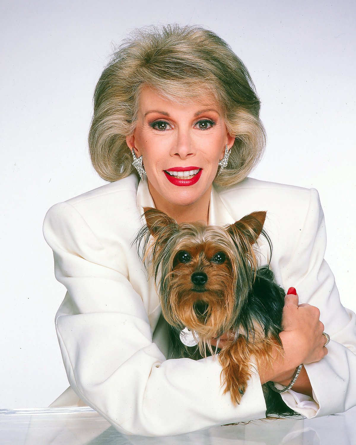 Joan Rivers with her arms around her Yorkshire Terrier on the table