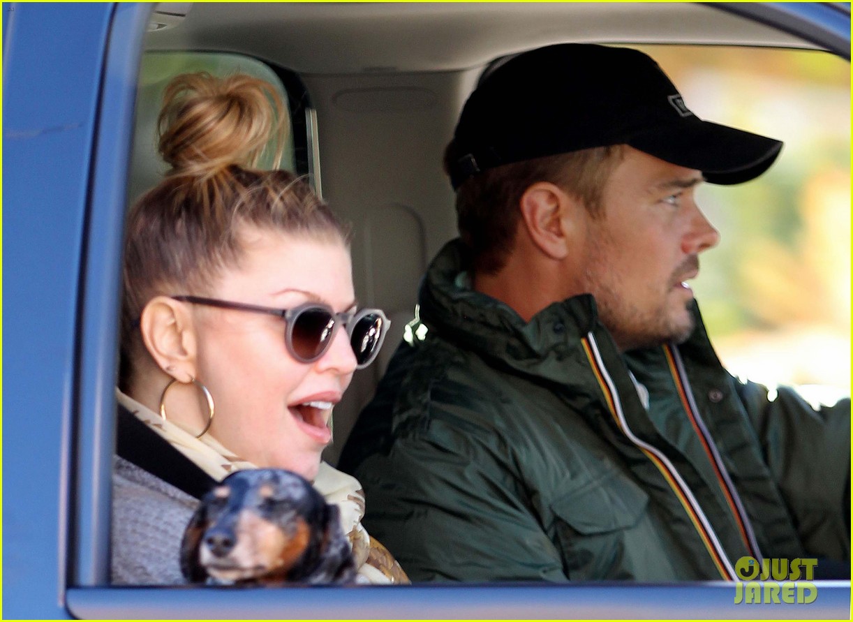Fergie & Josh Duhamel inside the car with their Dachshund in Fergie's lap while looking outside the car window