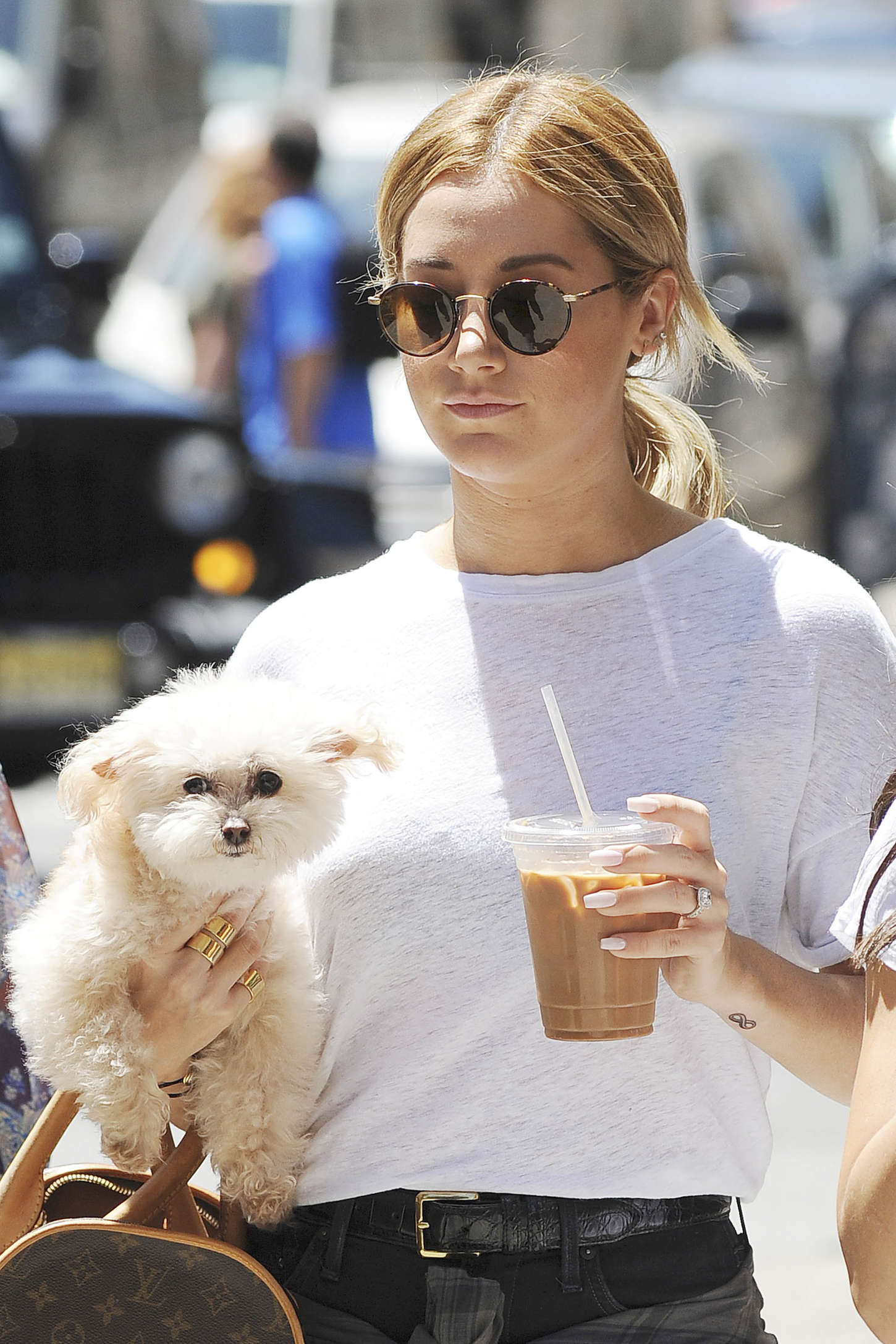 Ashley Tisdale walking in the street with an iced coffee in her hand and Bichon Frise puppy in her other hand