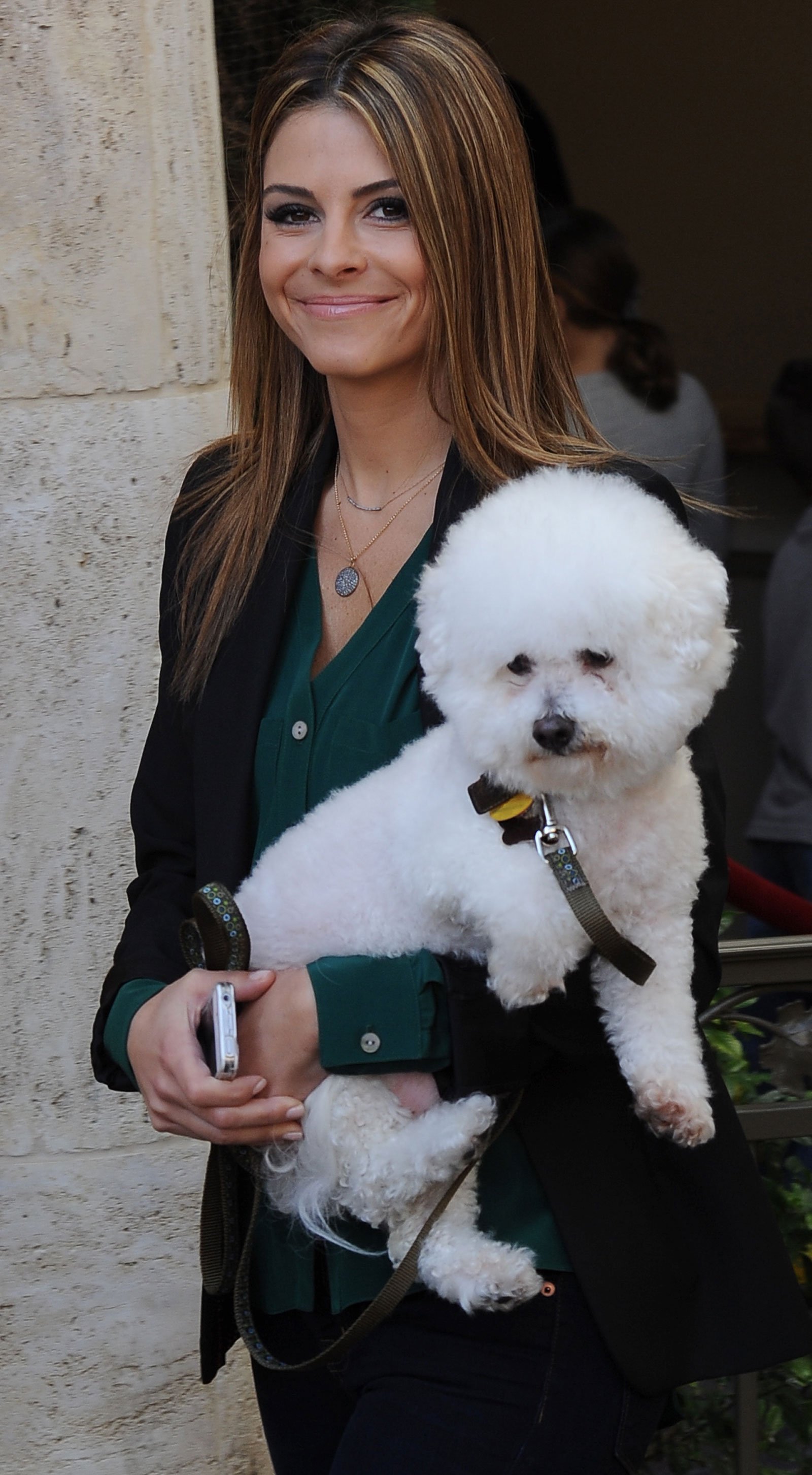 Maria Menounos smiling while carrying her Bichon Frise