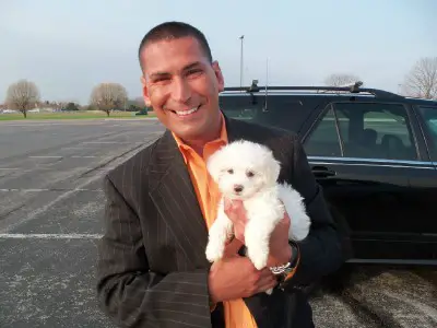 Paul Strong with a Bichon Frise puppy in his hands