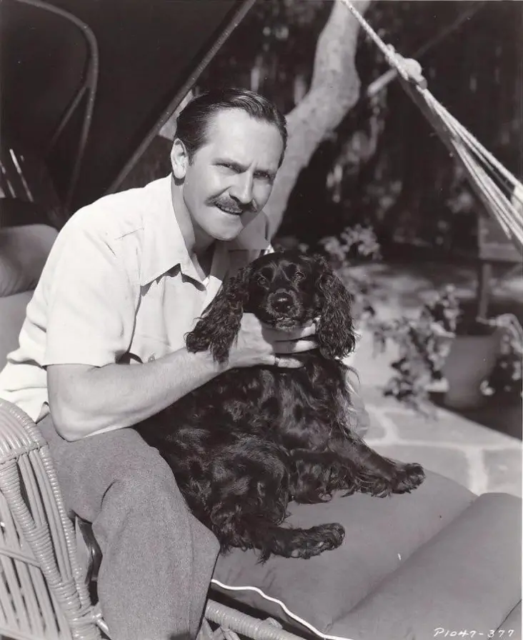 Fredric March sitting on the with his Cocker Spaniel