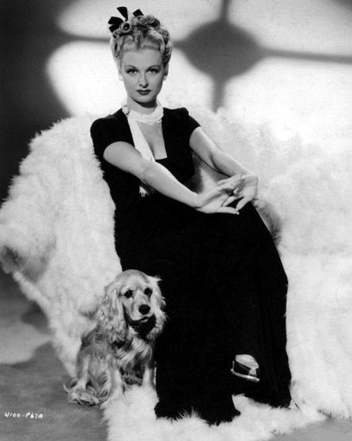 Joan Bennett sitting on a chair with Cocker Spaniel next to her on the floor