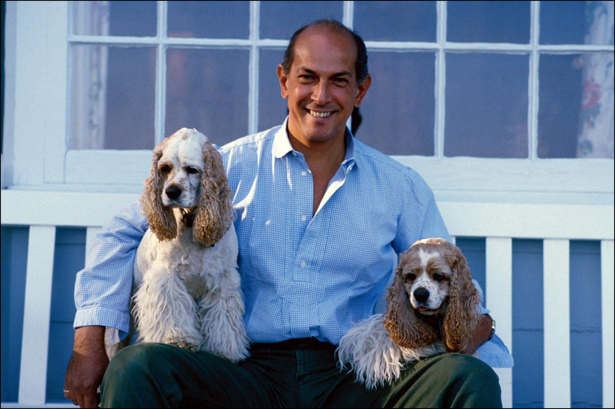 Oscar de la Renta sitting on the bench in between his two Cocker Spaniels