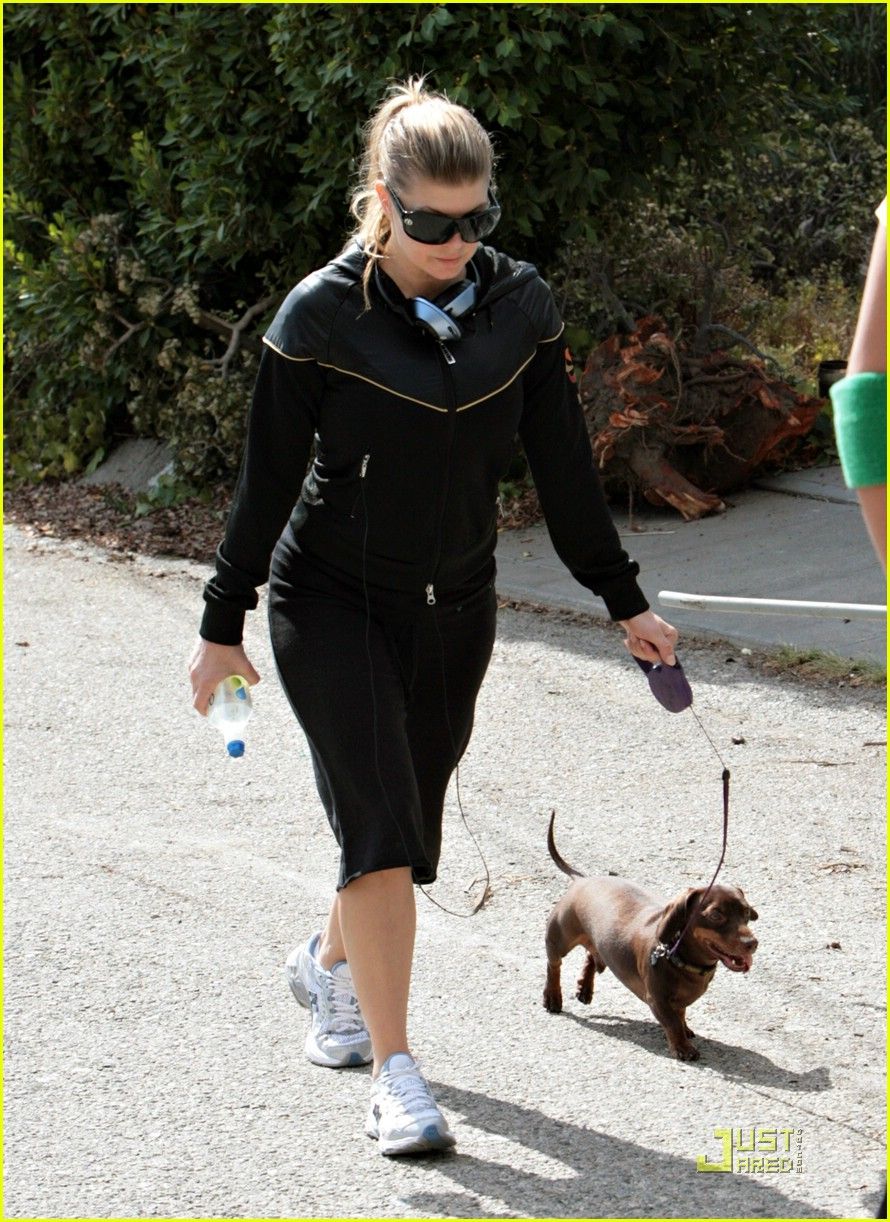 Fergie in her active wear taking her Dachshund for a walk in the street