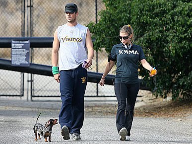 Fergie and Josh taking their Dachshund for a walk in the street