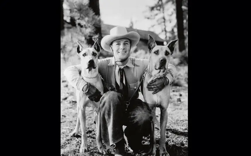 black and white photo of Randolf Scott in between his two Great Danes