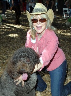 Barbara Eden kneeling on the ground with her Labradoodle