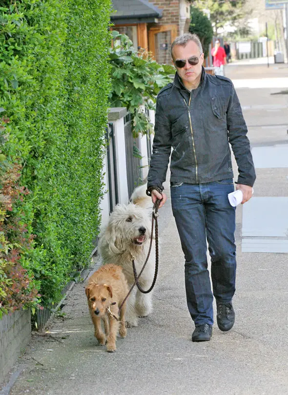 Graham Norton walking in the street with his labradoodle and another dog