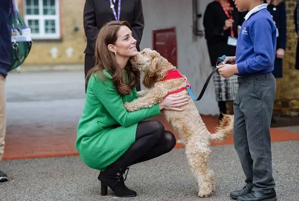Kate Middleton petting her labradoodle while smiling to the kid in front of her